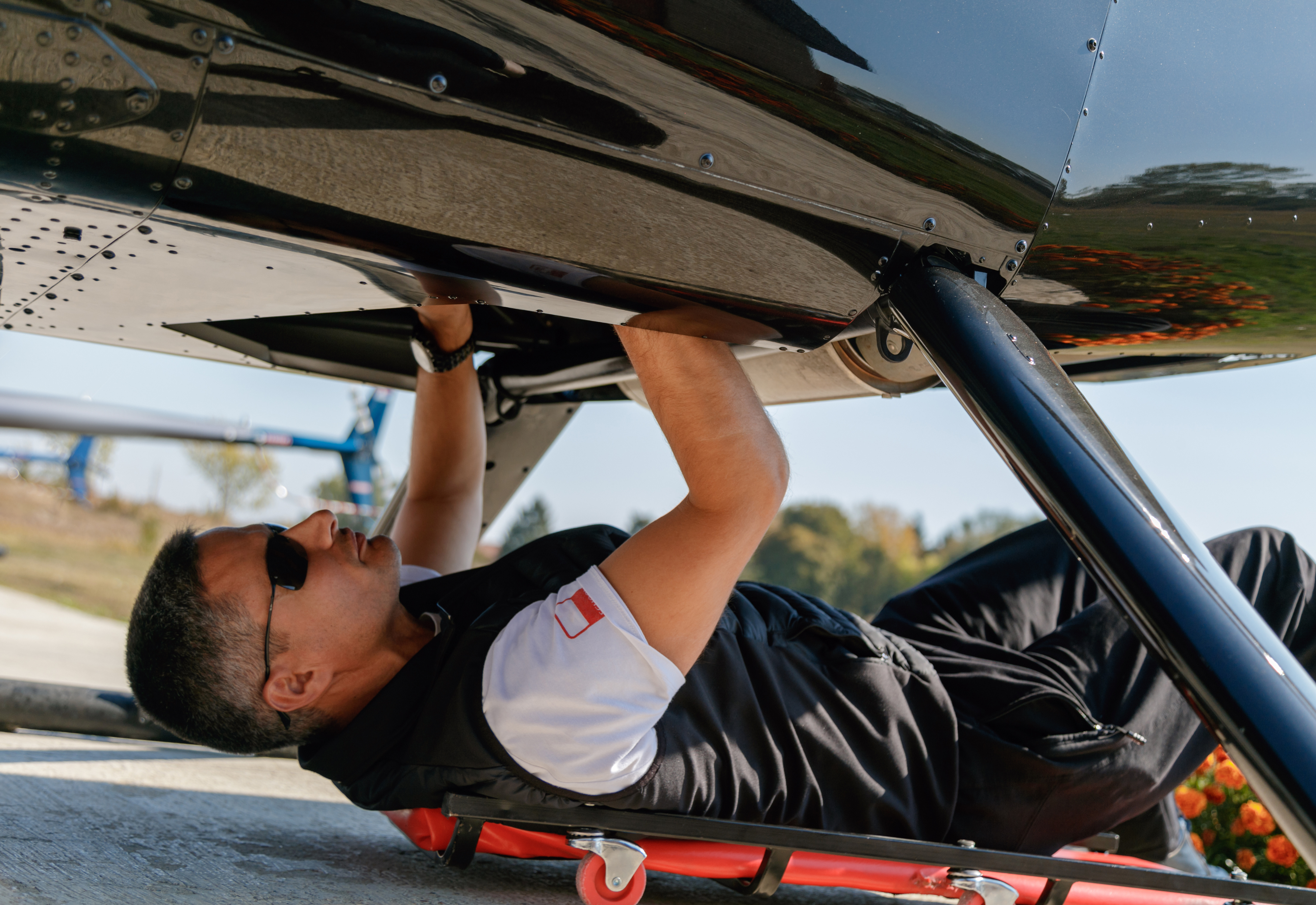 A helicopter mechanic carrying out repairs,  representing military contract work overseas. 